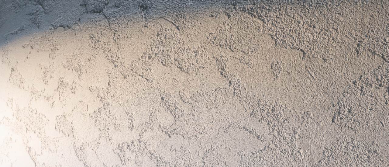 Detail of a knockdown ceiling texture showing flattened mottled plaster