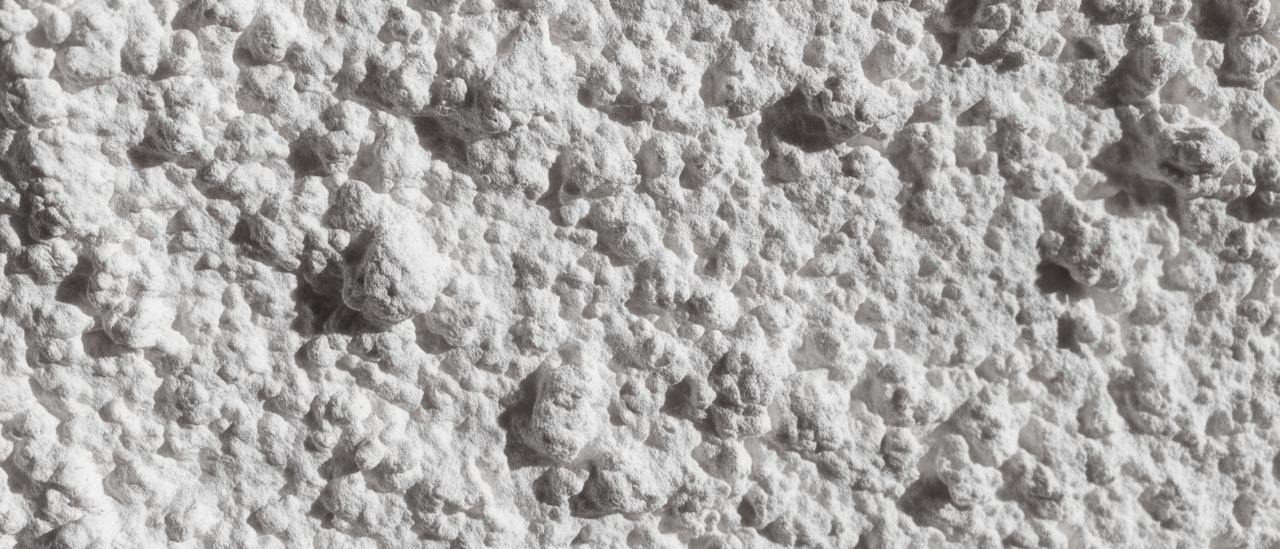 Close-up of white popcorn ceiling texture showing its rough peaked surface