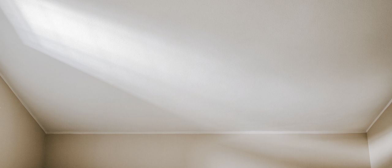 Freshly skim-coated smooth white ceiling meeting a clean wall line